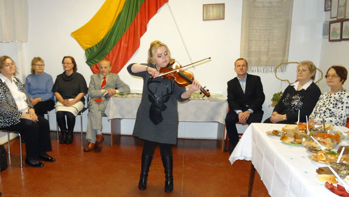 Kalėdų giesmes smuiku atlieka profesionali smuikininkė Jūratė Birgelytė.  Sėdi (iš kairės): Onutė Virbylienė, Gražina Kajackienė, Birutė Mockun, Pranas Sovulis, Kostas Jurkiūnas, Teklė Gibavičienė, Julija Prelevič